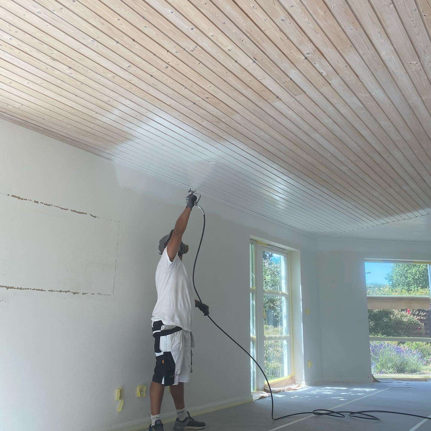 Maler hos Borregaards Malerfirma i gang med at spraymale et træloft